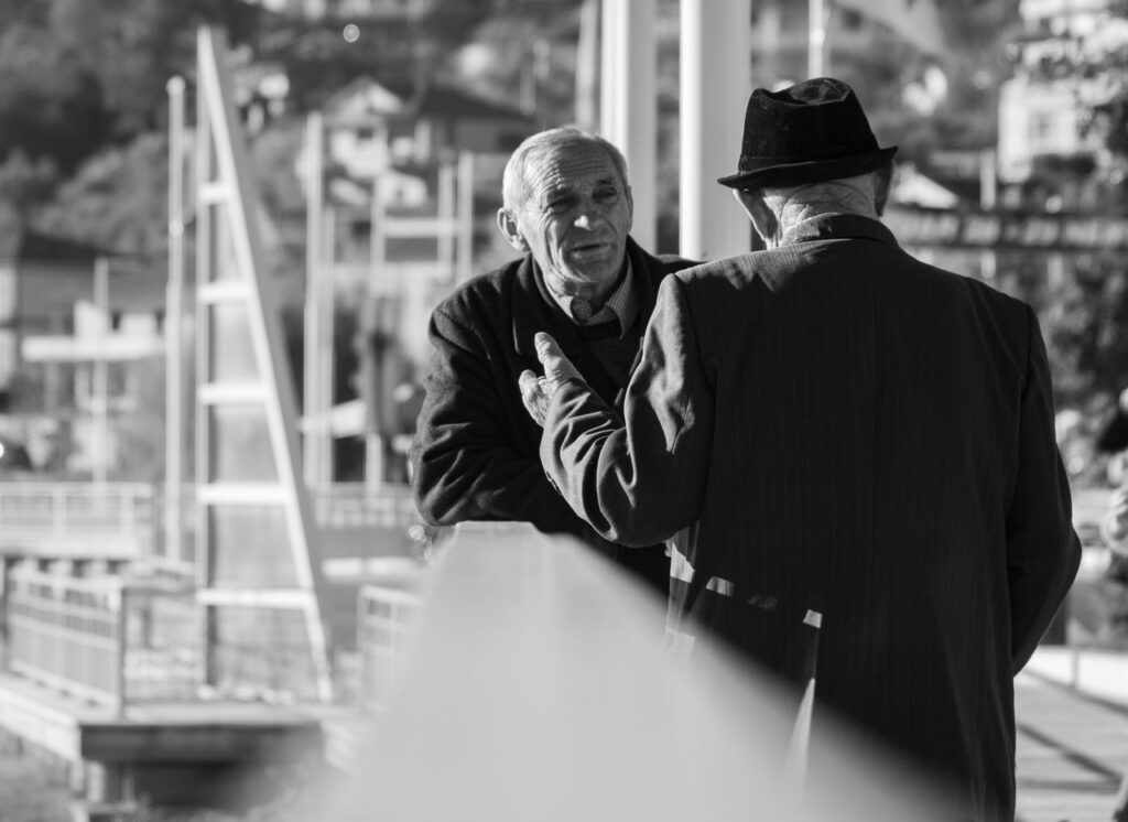 Two senior men engaged in conversation on a street in Elbasan, Albania. Acuerdo