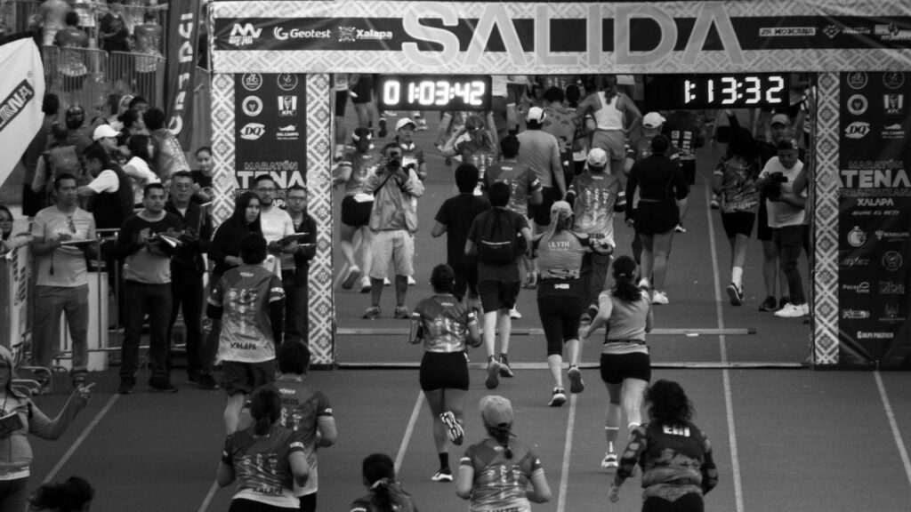 Participants running in a marathon race in Xalapa, Veracruz, captured in black and white. Acuerdo